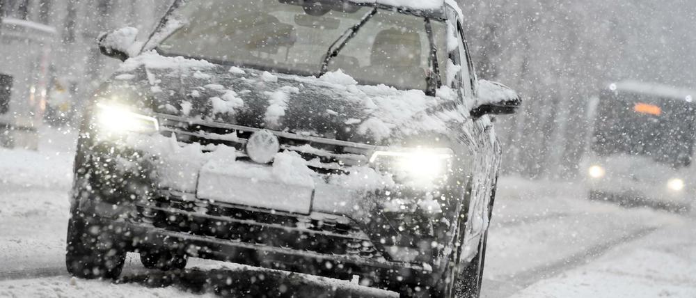 Bußgelder für Autofahrer im Winter: Ein Auto fährt bei Schneefall auf einer schneebedeckten Straße. (Archivbild)