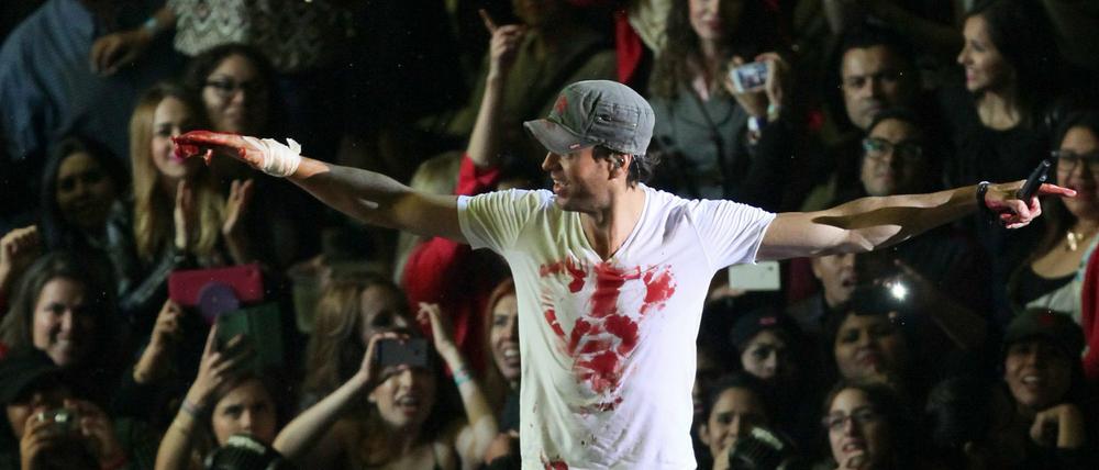Enrique Iglesias mit blutverschmiertem T-Shirt und verbundener Hand bei seinem Konzert am Samstag in Mexiko. Der Sänger hatte nach einer Drohne gegriffen und sich dabei so schwer verletzt, dass er sich einer Hand-OP unterziehen musste. 