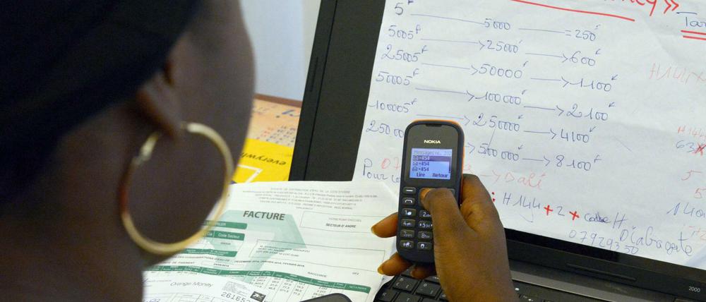 Eine Afrikanerin bezahlt mit dem Handy eine Rechnung. 
