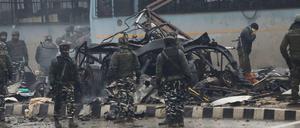 Indische Sicherheitskräfte inspizieren das ausgebrannte Fahrzeug nach einem Anschlag in Kaschmir.