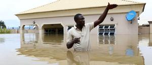 Ein Mann steht vor einem überfluteten Haus in der Nähe der nigerianischen Stadt Lokoja im Wasser.