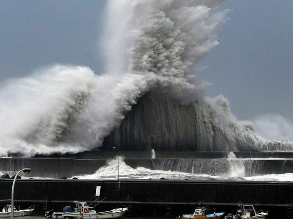 Hohe Wellen brechen an Wellenbrechern in einem Hafen von Aki.
