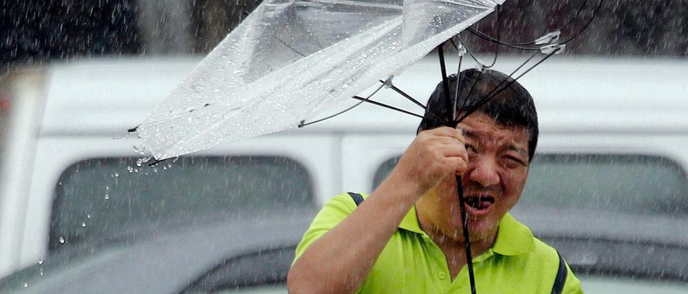 Ein Mann in Taiwan hält einen Regenschirm während der Taifun wütet. 
