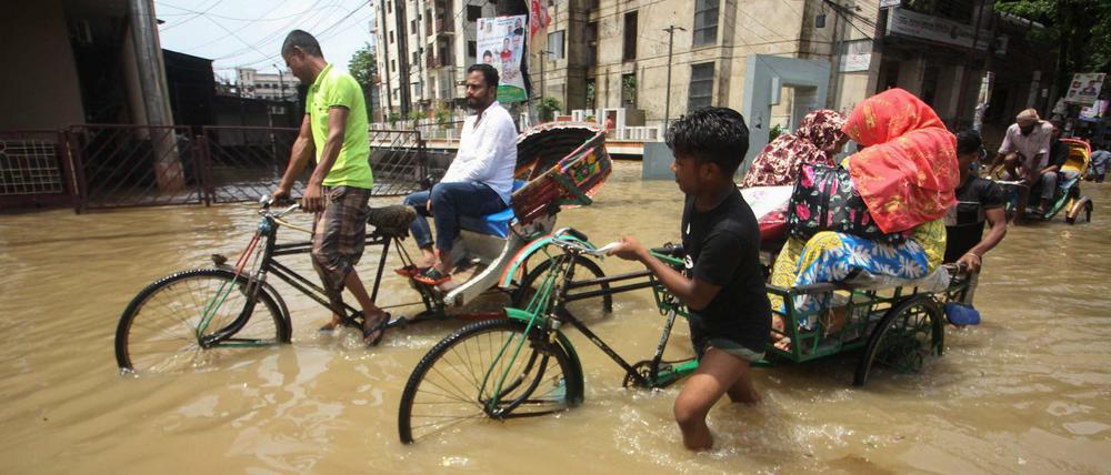 Rikscha-Fahrer kämpfen sich in Sylhet in Bangladesch durch überflutete Straßen.