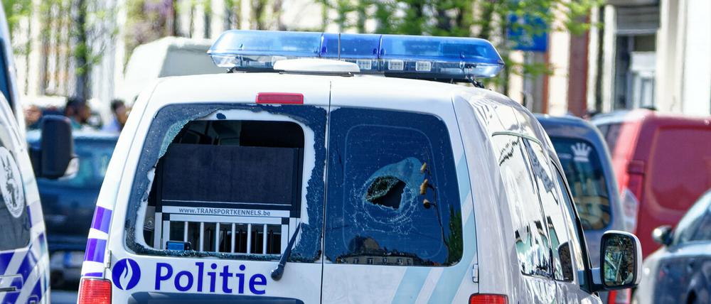 Ein Polizeiauto mit zertrümmerten Heckscheiben steht auf der Straße.