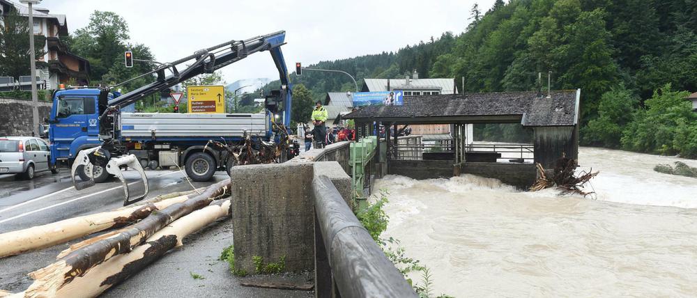 Ein Baumstamm wird bei Unwetter und Hochwasser in Bayern im Berchtesgadener Land aus dem Wasser geholt.