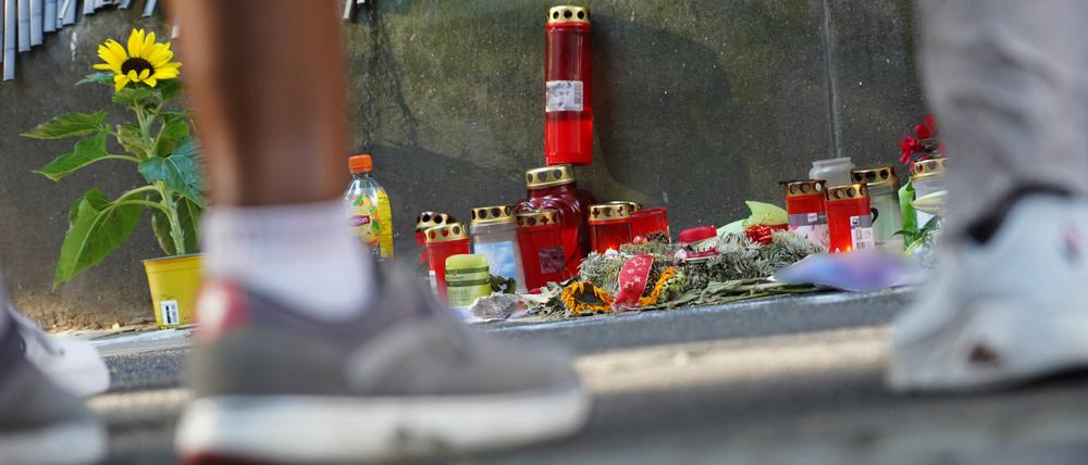 Zwei Menschen stehen vor einem Zaun, an dem mit Kerzen und Blumen eines von der Polizei erschossenen Jugendlichen gedacht wird.