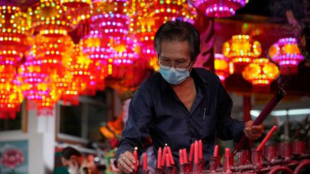 Ein Gläubiger hält Räucherstäbchen und stellt eine Kerze in einen Tempel anlässlich des chinesischen Neujahrsfest. 