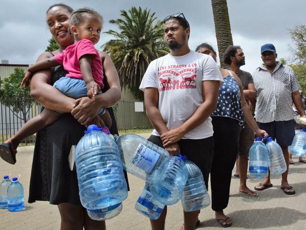 Anwohner stehen in Kapstadt mit Gallonen für Wasser an.