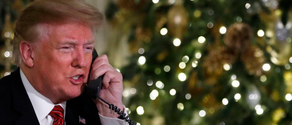 Donald Trump, Präsident der USA, sitzt am Telefon und gibt Updates über das Bewegungsprofil des Weihnachtsmannes.