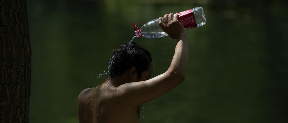 China, Peking: Ein Mann schüttet sich an einem heißen, schwülen Tag in der chinesischen Hauptstadt Wasser aus einer Flasche über den Kopf.