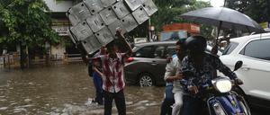 Menschen überqueren eine überschwemmte Straße im indischen Mumbai.