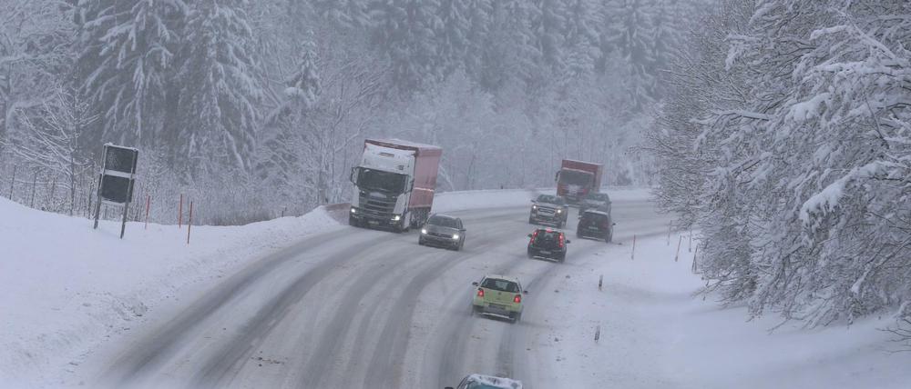 Autos fahren auf der schneeglatten Bundesstraße 12 in Bayern. 