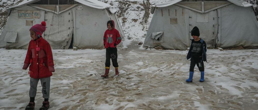 Syrische Kinder stehen in einem verschneiten Lager für syrische Binnenvertriebene. Der Wintereinbruch trifft sie am härtesten. 