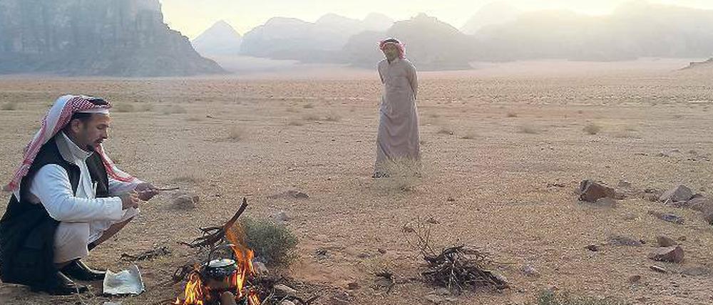 Kaffee zum Sonnenaufgang. Frühmorgens haben diese beiden Beduinen im Wadi Rum ein Feuer angezündet. Von hier starten Kameltouren. 
