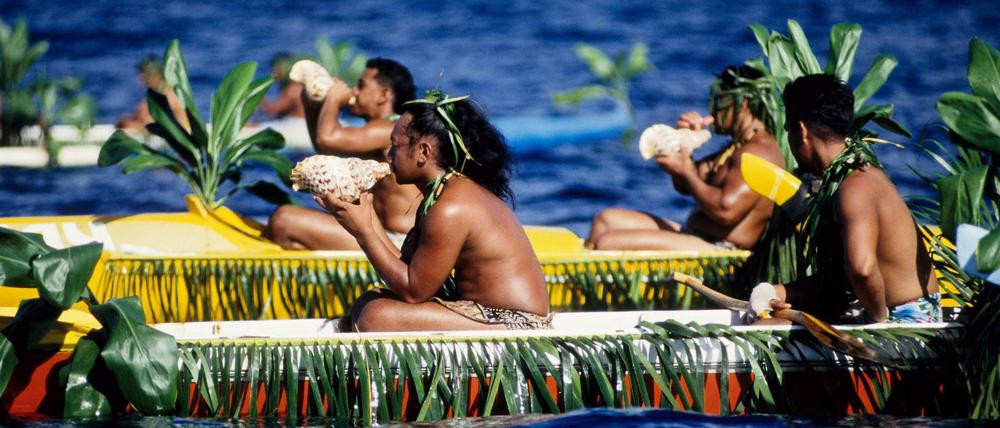 Polynesier mit Muschelhörnern in geschmückten Auslegerkanus anlässlich eines Inselfestes auf Nuku Hiva.