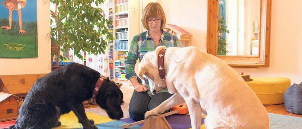 Spielen und üben. Die Logopädin Carola Schneider-Tobis mit ihren Therapiehunden Annuk (schwarzes Fell) und Clea. 
