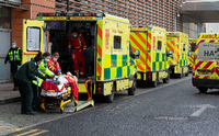 Eine Reihe von Krankenwagen vor einem Krankenhaus in England. Notärzte kümmern sich um einen neu angekommenen Patienten. Mark Thomas/imago images/i Images