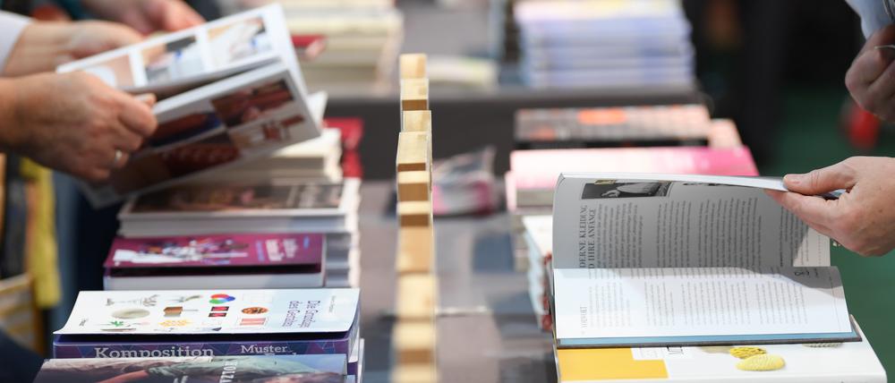 Besucher der Frankfurter Buchmesse blättern an einem Verlagsstand in Büchern.