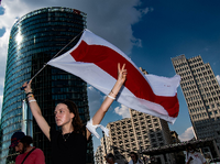 Viktoria steht mit der Fahne von Belarus auf dem Potsdamer Platz. Dort demonstrierten mehr als 100 Menschen gegen die Verletzung der Menschenrechte in Belarus - am Wochenende sollen es 1000 werden. Foto: Paul Zinken/dpa 