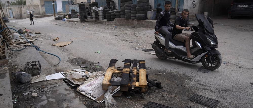 Palästinenser fahren auf einem Motorrad im Flüchtlingslager Aqabat Jaber an verbrannten Gegenständen vorbei.