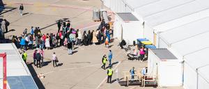 Menschen stehen im Berliner Ankunftszentrum für Flüchtlinge aus der Ukraine am ehemaligen Flughafen Tegel vor einem Zelt Schlange. 
