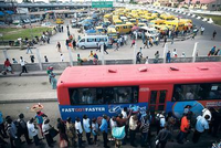 In Lagos stehen Menschen Schlange, um in einen Bus einzusteigen. Im Hintergrund sind Sammeltaxis zu sehen. Foto: Reuters