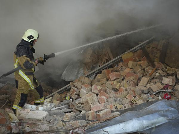 Feuerwehrleute löschen ein Feuer nach einem Drohnenangriff auf Gebäuden. 