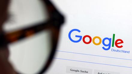 Die Seite der Suchmaschine von Google ist hinter einer Frau mit Brille zu sehen. 
