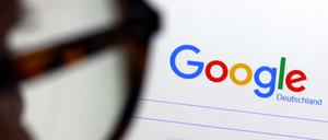 Die Seite der Suchmaschine von Google ist hinter einer Frau mit Brille zu sehen. 