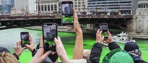 Zuschauer machen Fotos, während der Chicago River anlässlich der Feierlichkeiten zum St. Patrick’s Day in der Innenstadt von Chicago grün gefärbt wird.