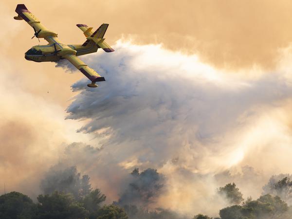 Ein Löschflugzeug versprüht Wasser, um einen Waldbrand auf der Insel Čiovo nahe Split zu löschen. 