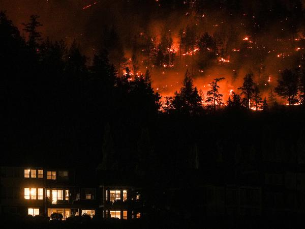 Das McDougall Creek-Wildfeuer in Kanada brennt am Freitag an einem Berghang oberhalb eines Hauses in West Kelowna.
