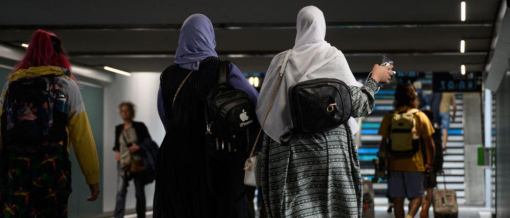 Frauen tragen Abayas, während sie durch eine Unterführung gehen. 