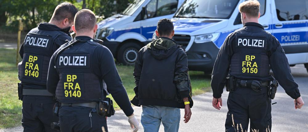 Ein unerlaubt eingereister Migrant wird durch Beamte der Bundespolizei nahe Forst (Lausitz) zum Fahrzeug geführt.