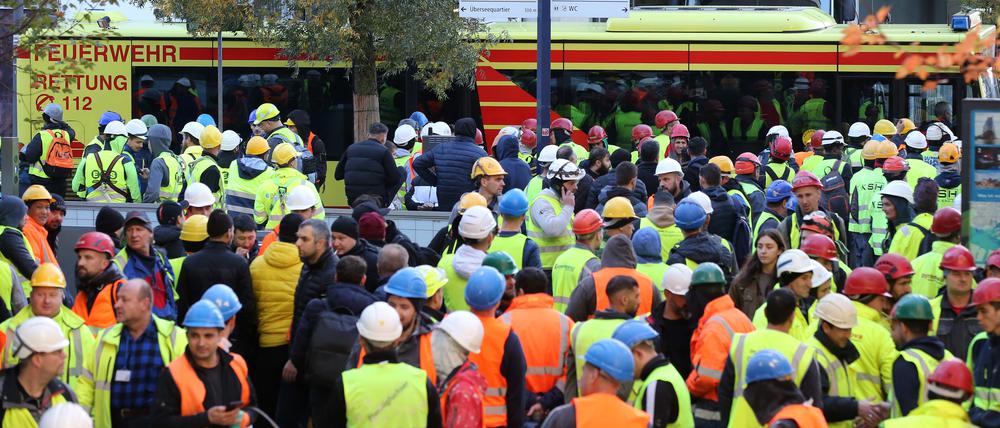 Einsatzfahrzeuge der Feuerwehr und zahlreiche Bauarbeiter stehen nach dem Unfall in der Hamburger Hafencity vor der Baustelle.