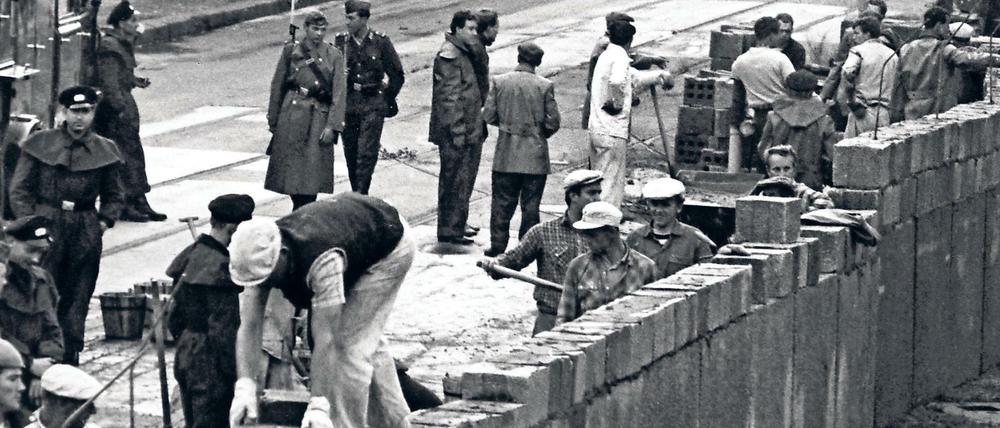 Unter der Aufsicht von bewaffneten Volkspolizisten errichtet eine Ostberliner Maurerkolonne am 18.8.1961 an der sowjetisch-amerikanischen Sektorengenze am Potsdamer Platz eine mannshohe Mauer.