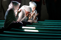 Bosnische Muslimas beten vor Särgen von Opfern des Massakers von Srebrenica, die in einer Gedenkstätte aufgestellt wurden, 2012. Foto: Amel Emric/dpa