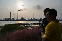 Ein Vater mit seinem Kind am Ufer des Huangpu gegenüber dem Wujing Kohlekraftwerk in Schanghai. Foto: Hector Retamal / AFP
