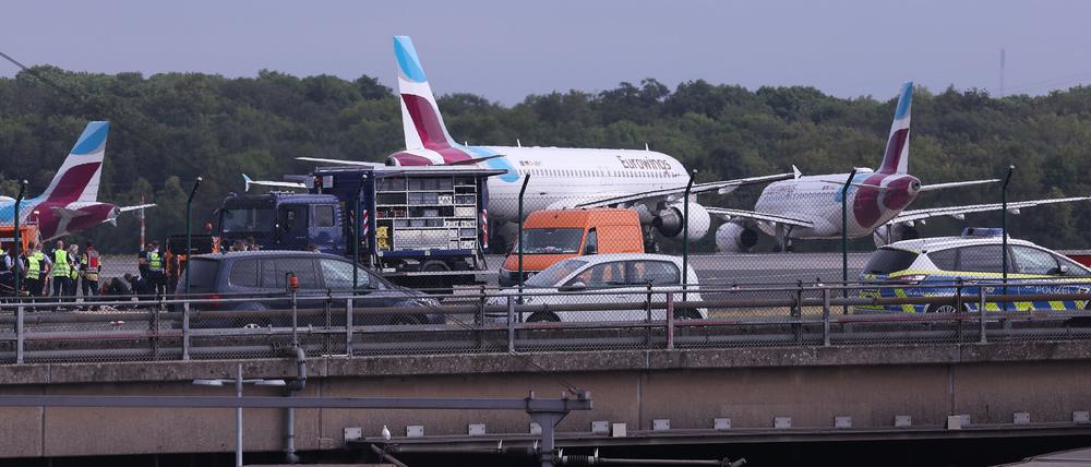 Polizisten stehen am Flughafen in Düsseldorf auf dem Flugfeld und versuchen Aktivisten der Gruppe „Letzte Generation“ vom Asphalt zu lösen, nachdem sie sich festgeklebt hatten. 