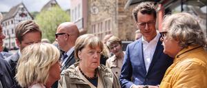 Die ehemalige Bundeskanzlerin Angela Merkel (M, CDU), Hendrik Wüst (2.v.r. CDU), Ministerpräsident Nordrhein-Westfalen, Bürgermeisterin Sabine Preiser-Marian (l, CDU) sprechen in Bad Münstereifel mit dem Cafehaus Besitzer Günter Portz (r).