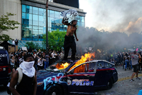 Ein Demonstrant steht auf einem brennenden Polizeiauto in Atlanta. = Foto: Elijah Nouvelage/AFP