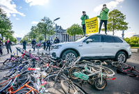 Aktivisten von Greenpeace demonstrieren vor dem Reichstag mit einer Aktion, bei der ein Auto über Fahrräder fährt. Mit Protestaktionen soll gegen eine erneute Abwrackprämie für Diesel und Benziner demonstriert werden. Foto: Michael Kappeler/dpa