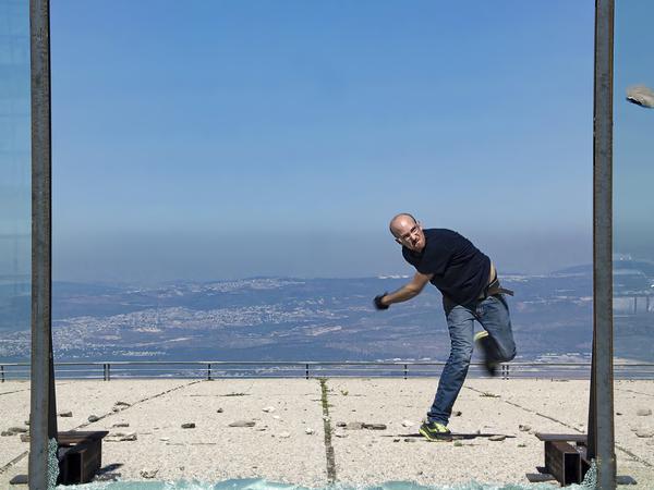 Wut auf Ungerechtigkeit. Avner Pinchover wirft in seiner Performance „Riot Glass“ Steine auf eine Glaswand vor einer Landschaft im Norden Israels.