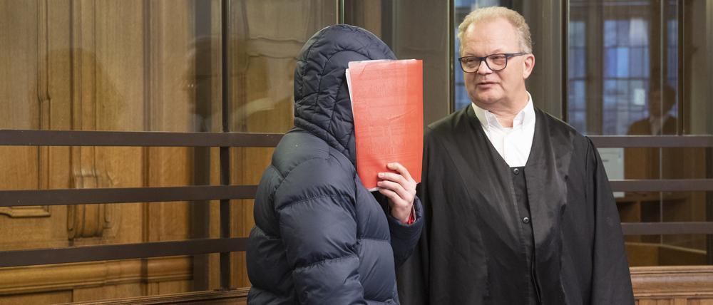 Der 25-jährige Angeklagte hält sich im Gerichtssaal eine Mappe vor das Gesicht.