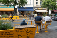 Passanten sitzen in einem Parklet an der Bergmannstraße in Kreuzberg. Paul Zinken