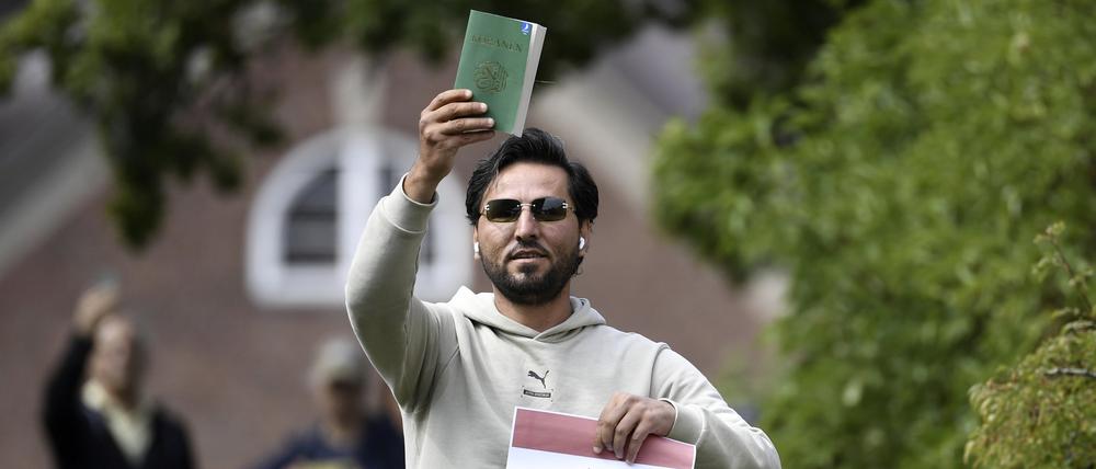 Salwan M.  hält eine Kopie des Korans, die er mutmaßlich gemeinsam mit einer irakischen Fahne vor der irakischen Botschaft in Stockholm verbrennen will.