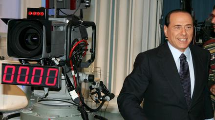 Silvio Berlusconi steht während einer TV-Produktion neben einer Fernsehkamera (Archivfoto vom 08.03.2006). Der italienische Medienkonzern MFE-Mediaforeurope hält inzwischen 28,9 Prozent an ProSiebenSat.1. 
