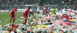 Fußballfans werfen Stofftiere als Zeichen der Solidarität auf den Rasen. 
