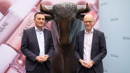 Sander van der Laan (l), CEO von Douglas und Finanzchef (CFO) Mark Langer stehen beim Börsengang der Douglas AG vor der Börse an der Bullen-Skulptur. 